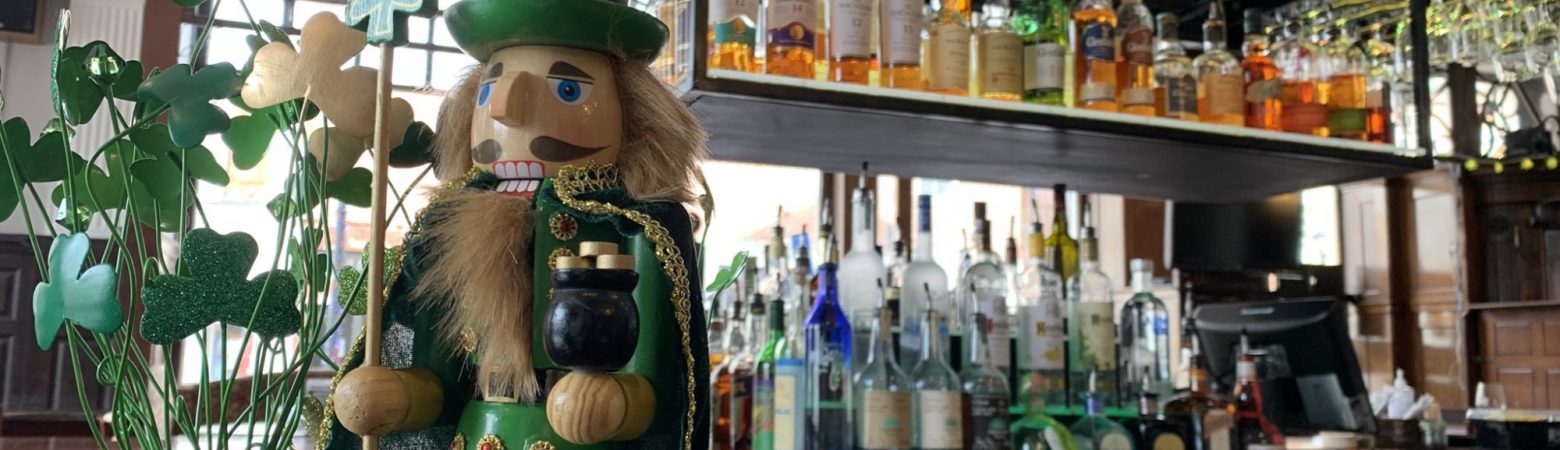 St. Patrick's Day nutcracker on a bar with liquor in the background