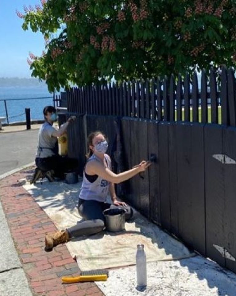 two people painting a fence
