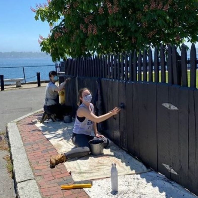 two people painting a fence